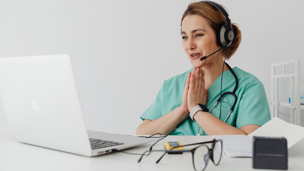 Médica feliz em frente ao computador. Imagem simboliza o atendimento pela telemedicina com ajuda da IA.